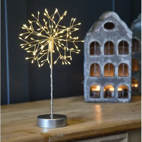 Decorative light fixture resembling a dandelion on a wooden surface with a dark background.